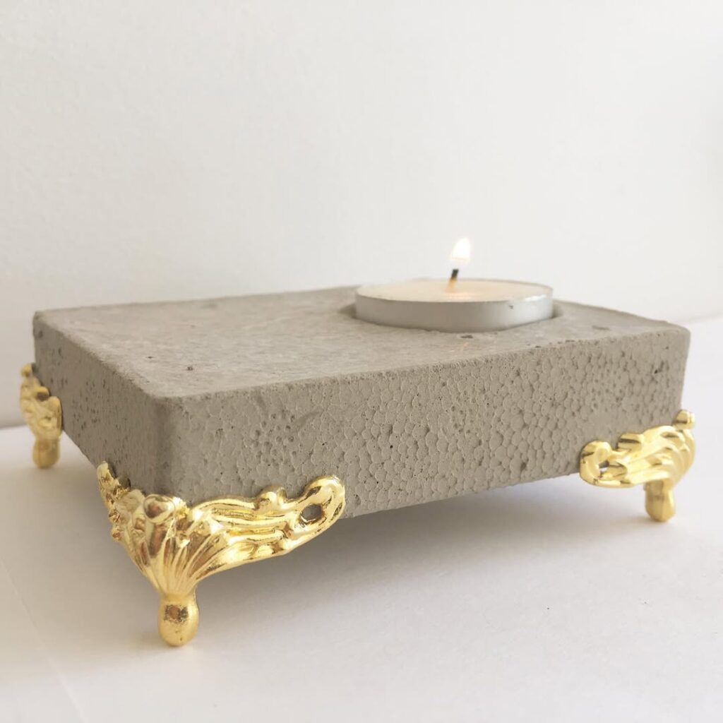 Porta-vela de concreto com pés dourados