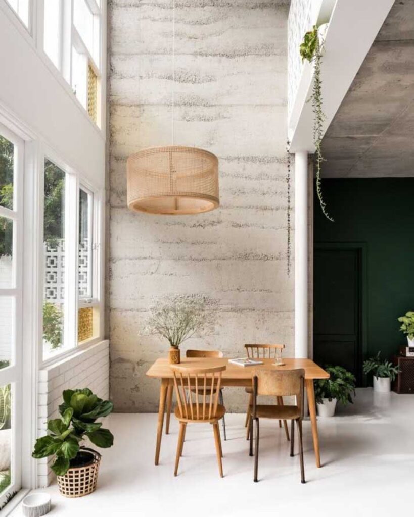 Varanda com concreto aparente, mesa e cadeiras de madeira e pendente de fibras naturais