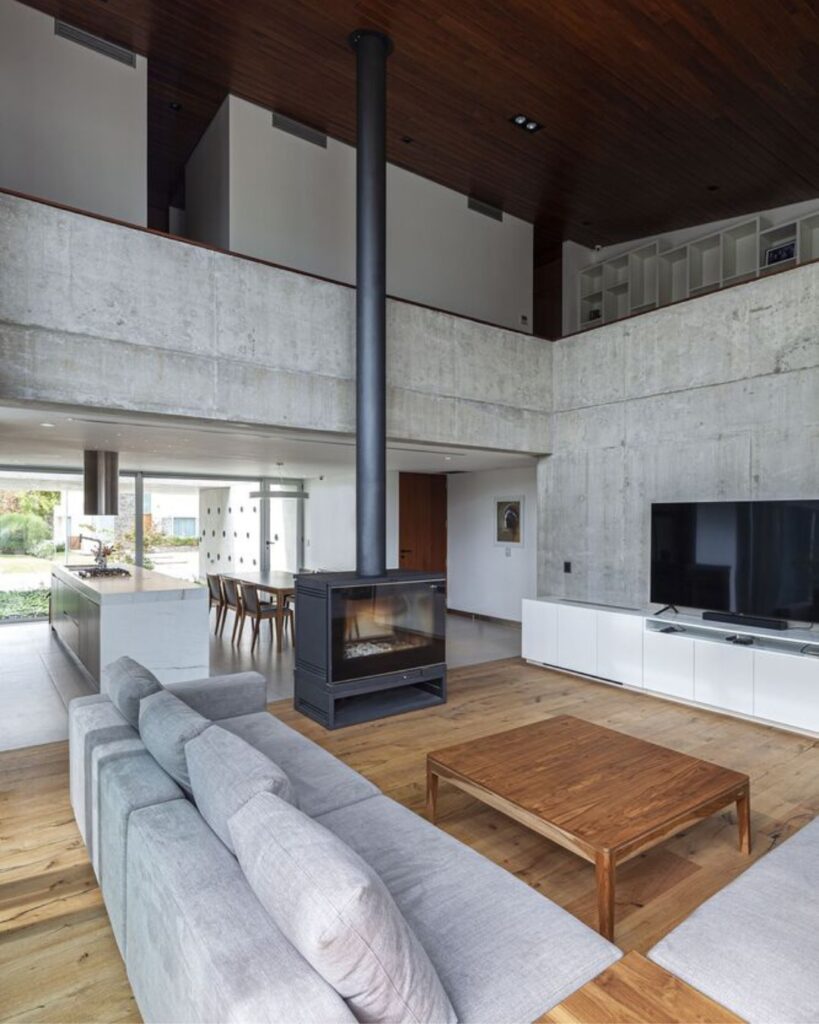 Sala de estar com pé-direito alto e concreto aparente nos revestimentos