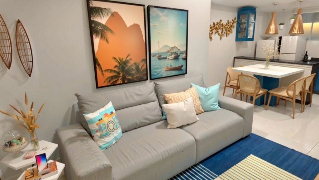 Sala de estar e jantar integradas com sofá cinza, amofadas e quadros com paisagens