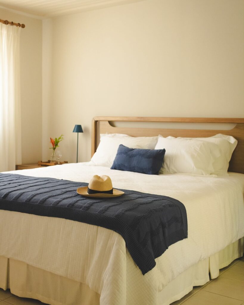Quarto com cama de casa de madeira, lençóis brancos e manta azul