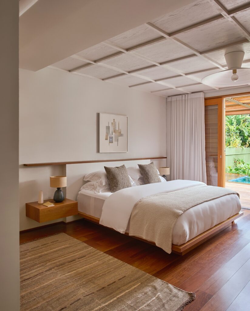 Quarto branco com detalhes amadeirados e mesa de cabeceira suspensa