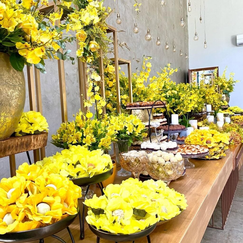 Mesa de madeira decorada com flores amarelas e doces