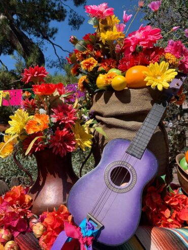 Violão roxo, jarro com flores coloridas e frutas