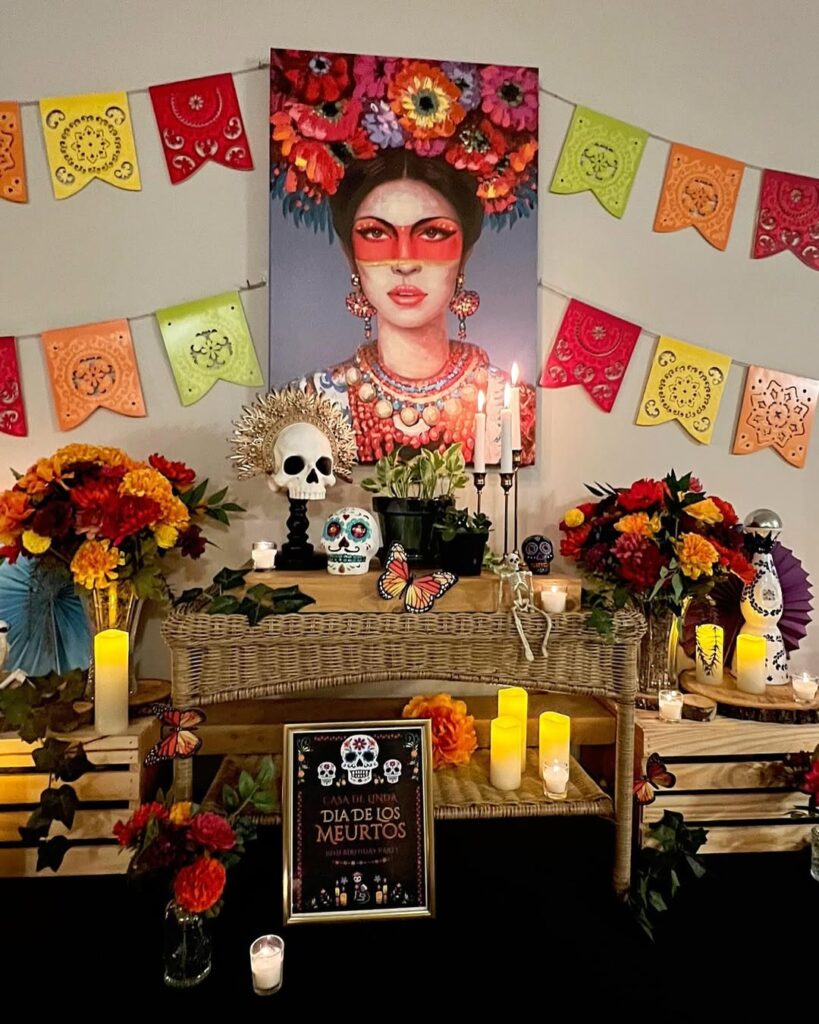 Ambiente decorado para o dia de los muertos com aparador, flores coloridas, velas, bandeirinhas