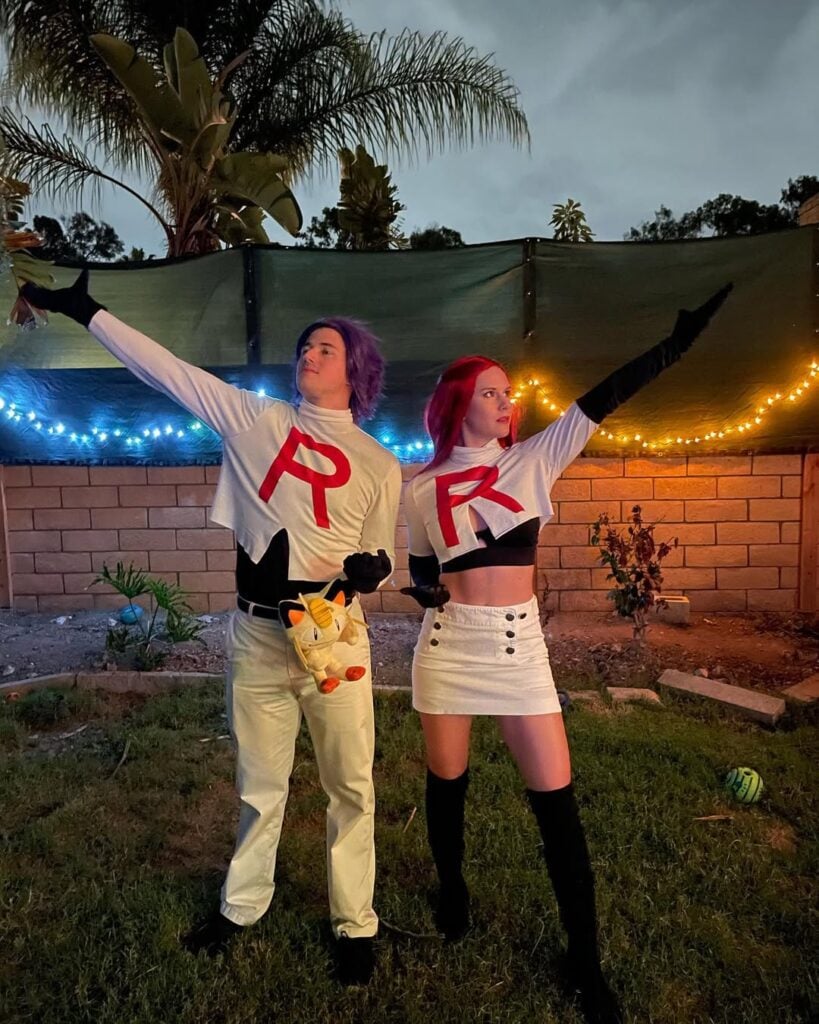 Casal fantasiado com roupa branca e com uma blusa com a letra R
