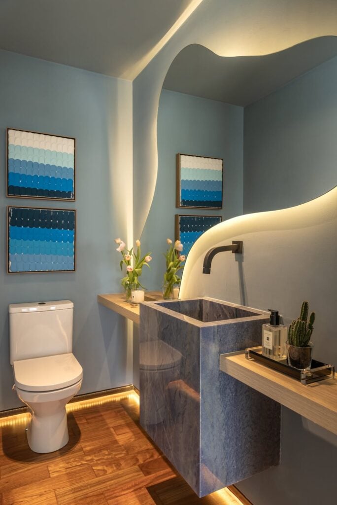 Lavabo com espelho orgânico, cuba quadrada cinza e quadros na parede
