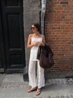 Mulher jovem com conjunto claro, óculos de sol e chinelo de dedo