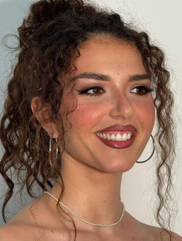 Mulher de pele negra-clara, com cabelo cacheado e maquiagem com sardas fakes