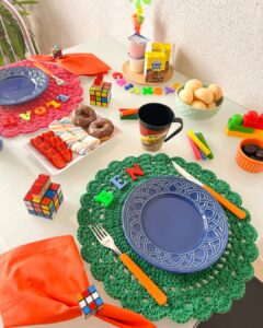 Mesa posta de dia das crianças com sousplats de crochê rosa e verde