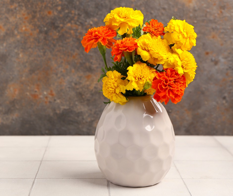 Vaso branco com flores laranjas e amarelas