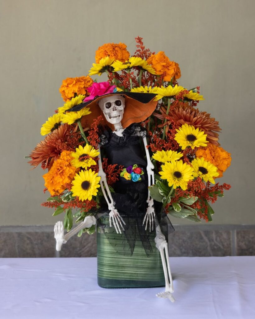 Vaso com flores amarelas e laranjas com um esqueleto