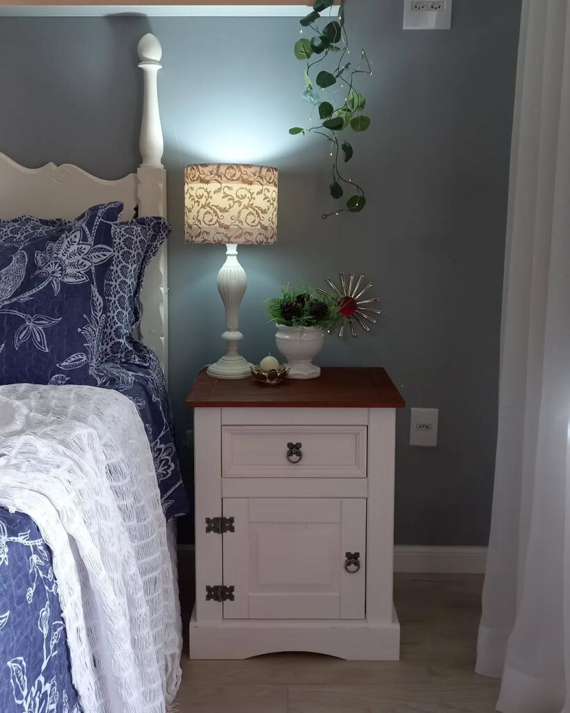 Quarto com cabeceira branca ornamentada e mesa de cabeceira branca com tampo de madeira