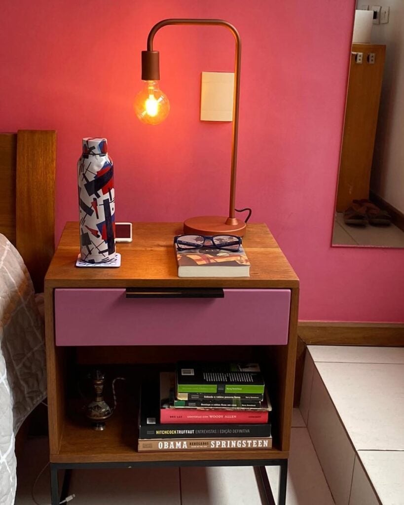 Mesinha de cabeceira de madeira com gaveta rosa e livros