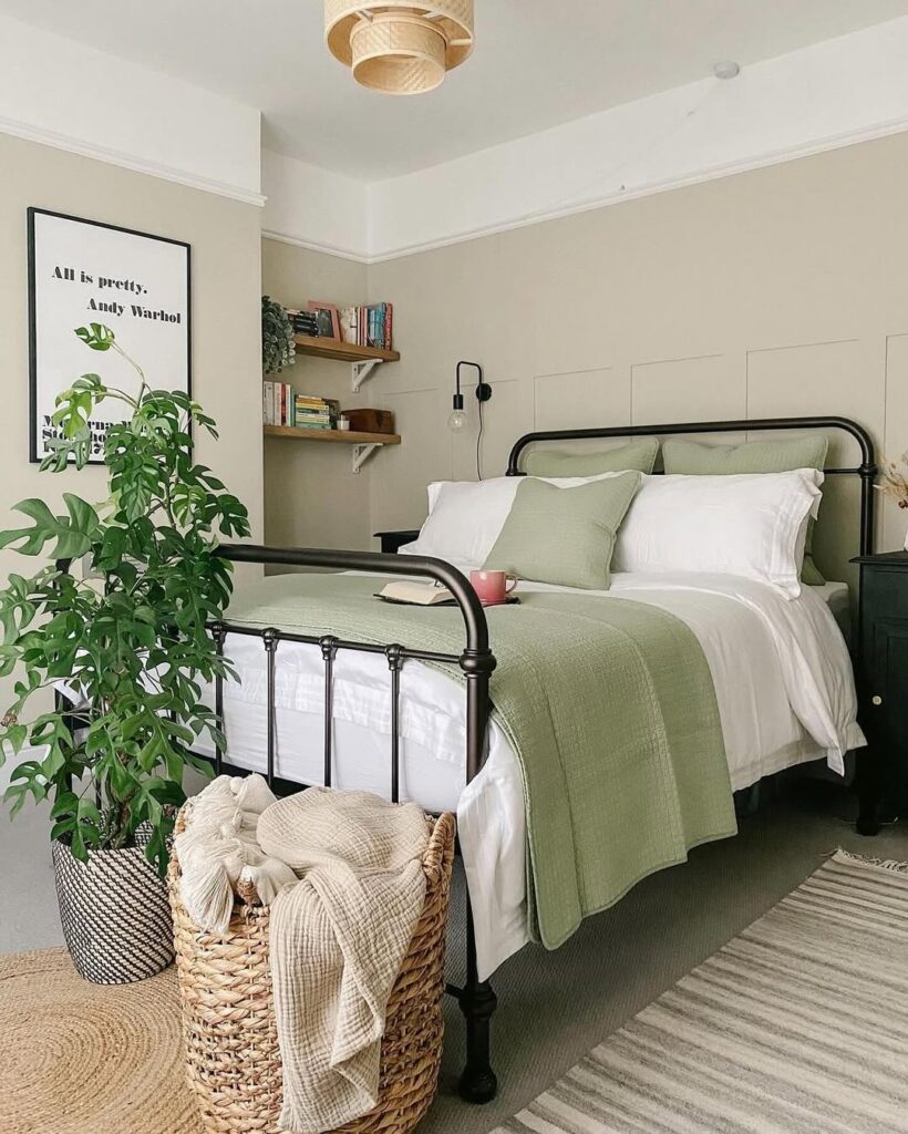 Quarto de casal com cama de ferro preta, luminária de fibras naturais, cesto de vime e vaso com plantas