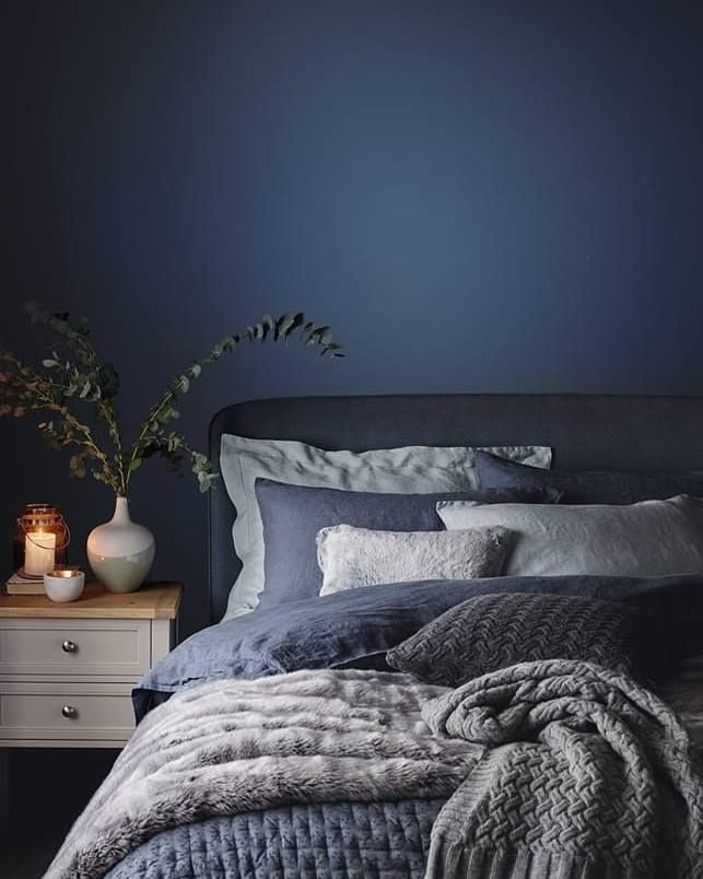 Quarto com parede, cabeceira e roupa de cama em tons de azul