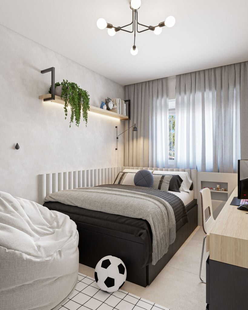 Quarto para adolescente menino, com cama, mesa de estudos, prateleiras, pufe, roupeiro, cabeceira, cortina, TV e decoração de bonecos na parede. Os tons são de madeira, preto e cinza e a decoração tem elementos de futebol