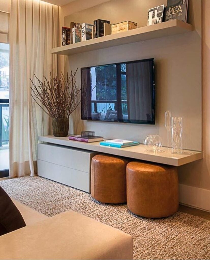 Sala com dois pufes marrons de couro embaixo do painel da tv