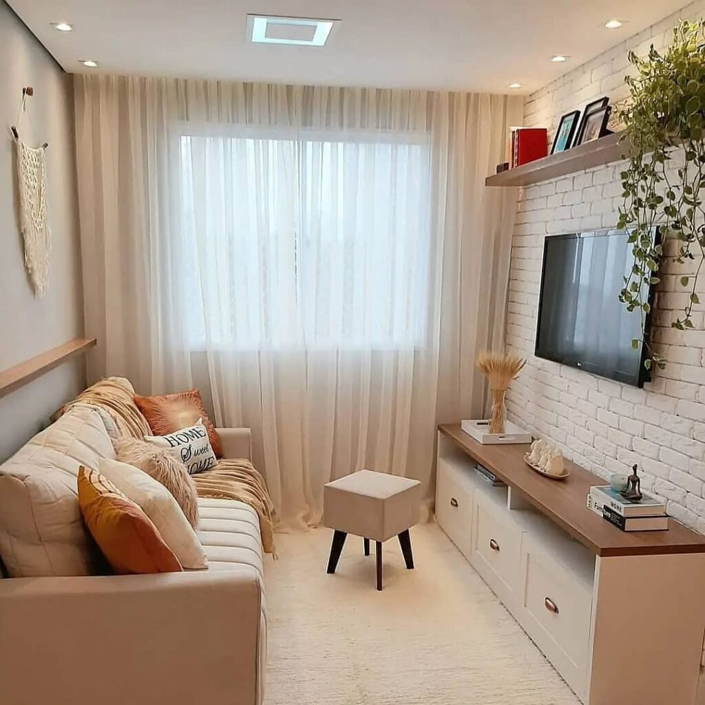 Inspiração de sala compacta com sofá bege com almofadas, rack de tv branco com tampo de madeira e parede de tijolinhos