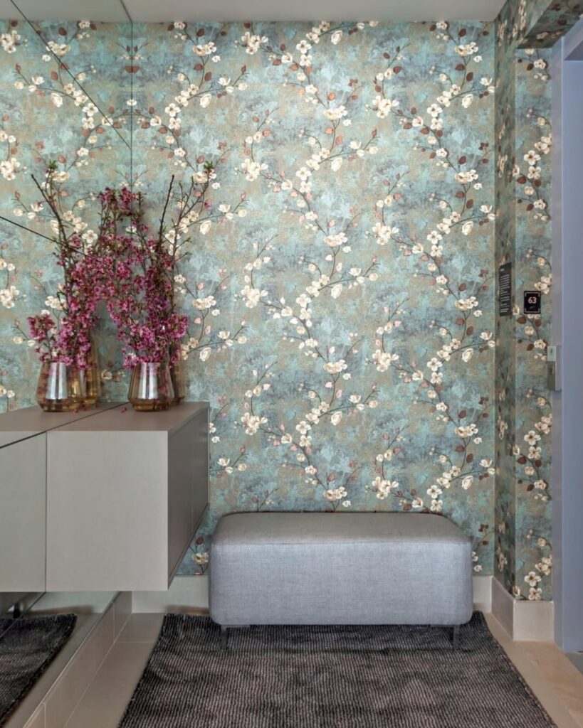 Ambiente com papel de parede floral, sapateira suspensa em tom fendi e banco ao lado