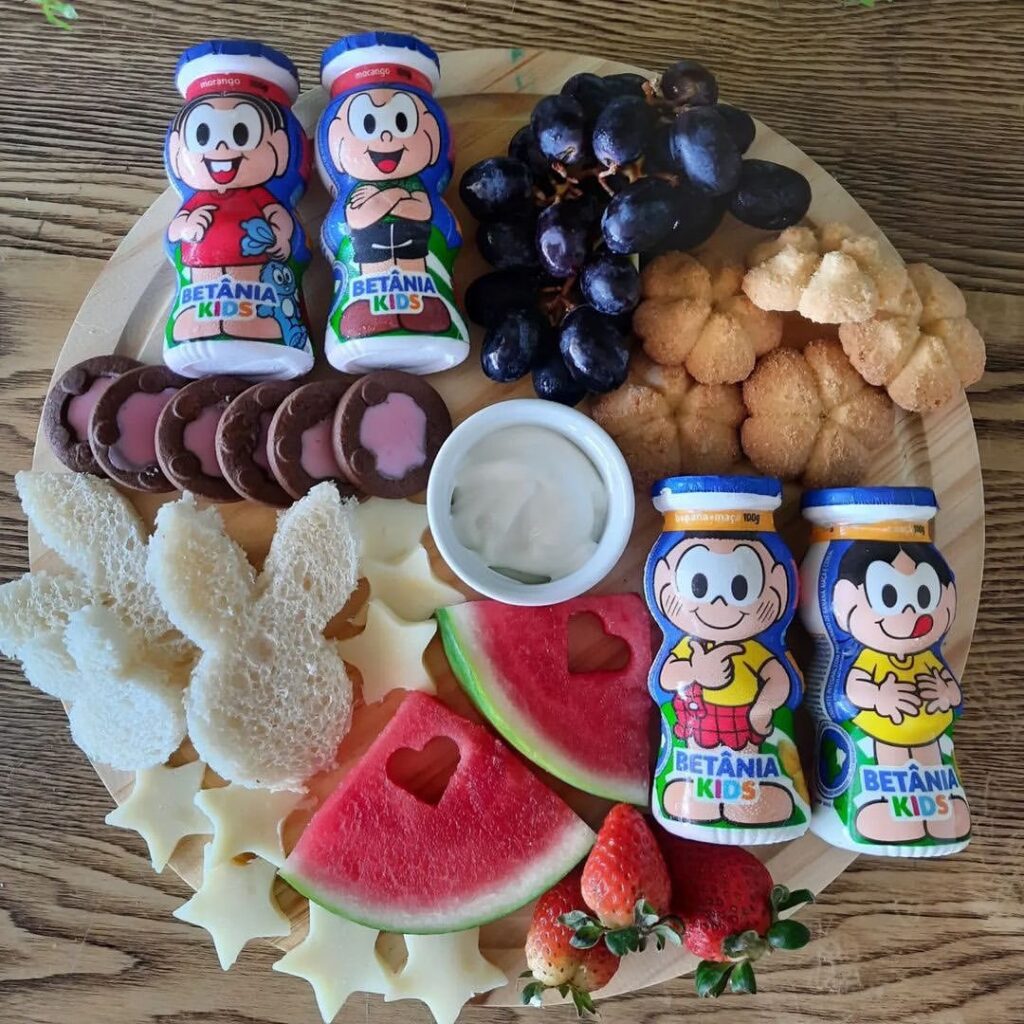 Tábua redonda com uvas, melancia, iogurtes e biscoitos