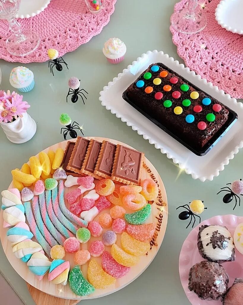 Mesa para o Dia das crianças com bolo de chocolate e tábua de madeira com balas e outros doces