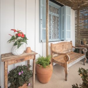 Varanda gourmet charmosa com parede de madeira, móveis de madeira e vaso de cerâmica com plantas e flores