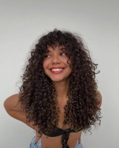 Mulher de pele preta, com cabelo escuro e corte wolf