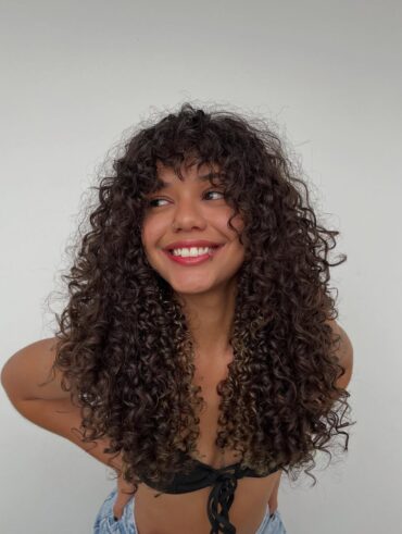 Mulher de pele preta, com cabelo escuro e corte wolf