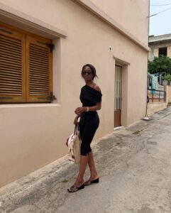 Mulher jovem e magra usando look todo preto e salto Anabela preto