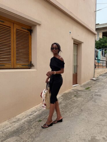 Mulher jovem e magra usando look todo preto e salto Anabela preto