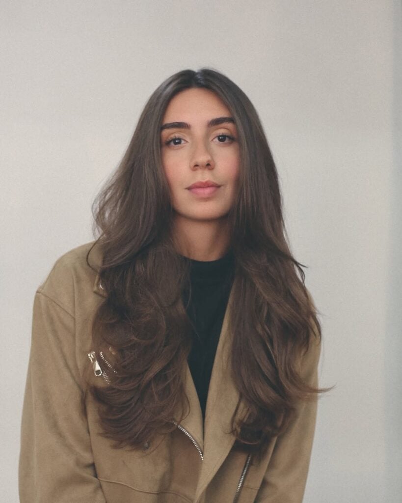 Mulher de pele clara com cabelo escuro longo e liso em camadas