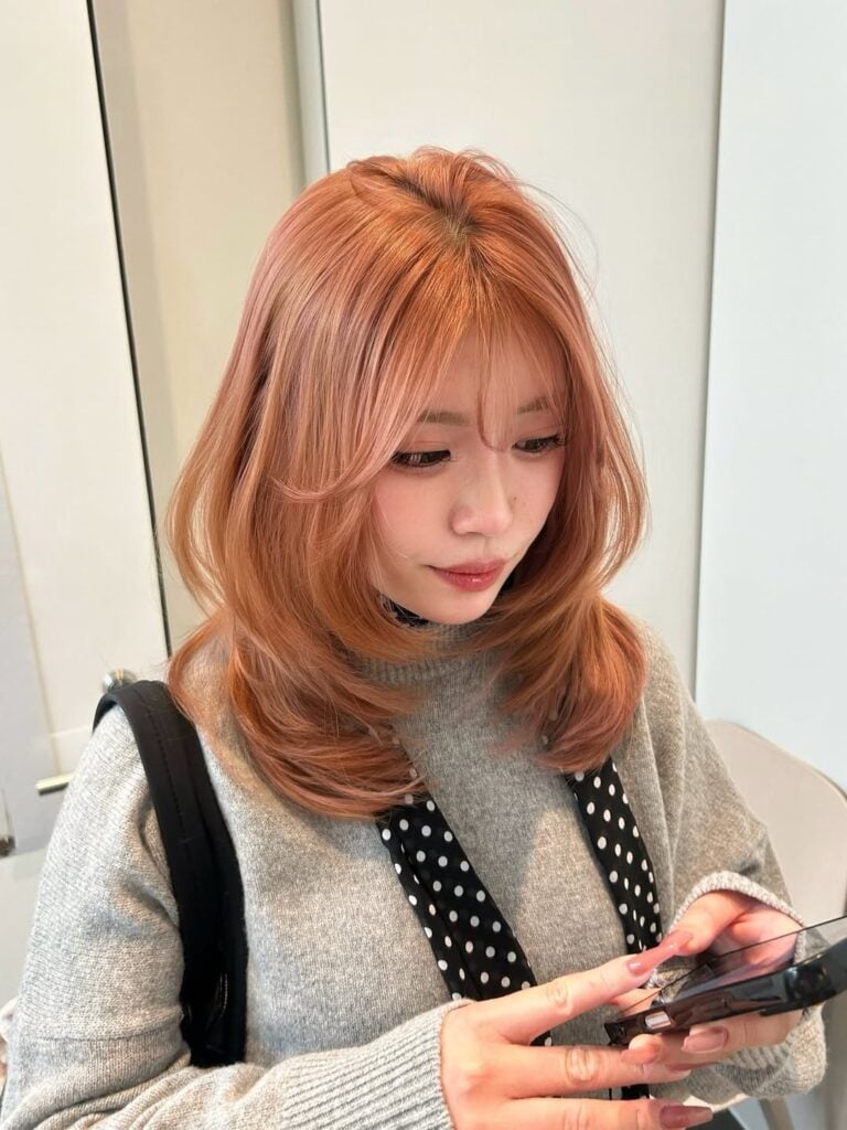Mulher de pele clara, com cabelo médio ruivo com corte em camadas