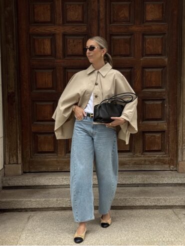 Mulher de pele clara, com blusa branca, casa bege e calça barrel jeans com sapatilha