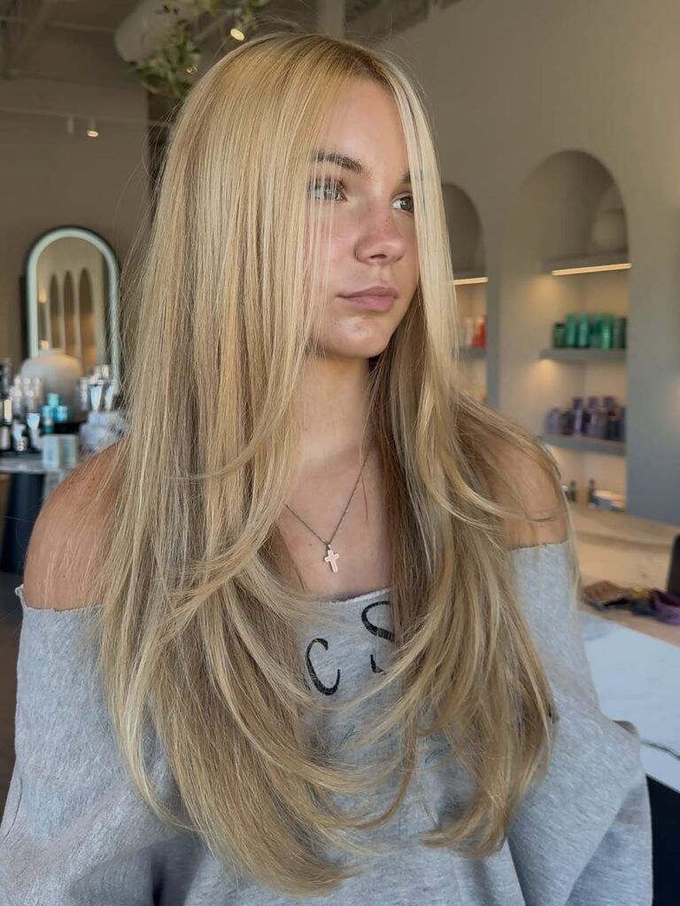 Mulher de pele clara, com blusa cinza e cabelo loiro com pontas desfiadas