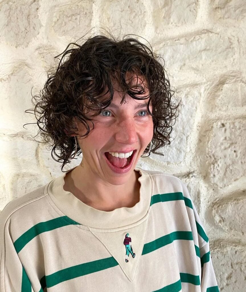 Mulher de pele clara, com blusa listrada e cabelo curto cacheado