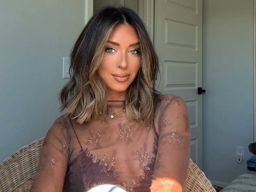 Mulher de pele clara, com blusa com transparência e cabelo curto 