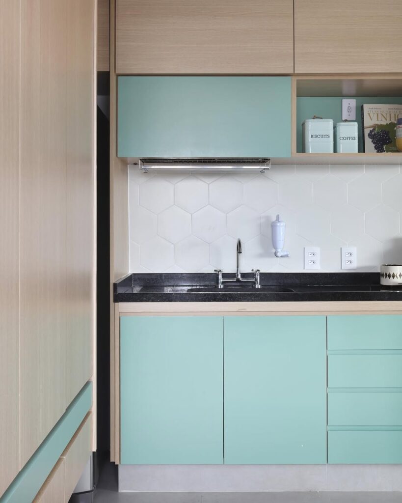 Cozinha verde-água com bancada preta e frontão branco