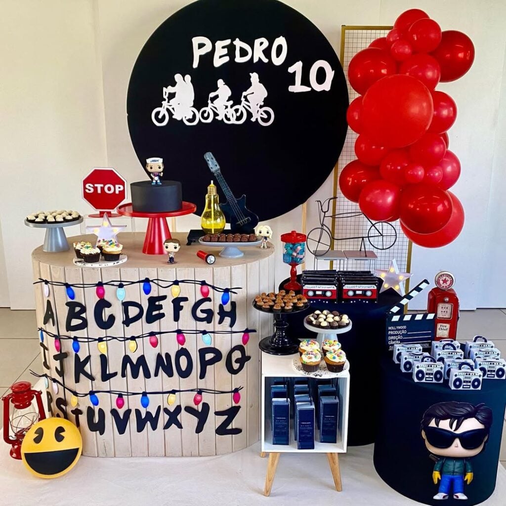 Aniversário temático de Stranger Things com balões vermelhos, bonequinhos, guitarra, abecedário com luzes