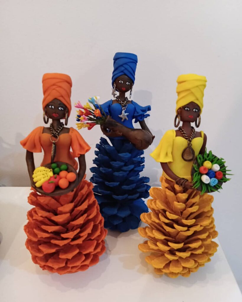 Bonecas decoradas com pinhas como saia nas cores laranja, azul e amarelo