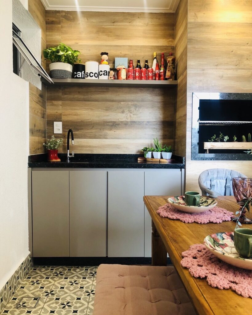 Ambiente com pia, painel amadeirado e churrasqueira