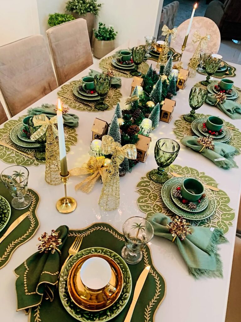 Mesa posta de Natal com mini árvores verdes, castiçais e itens dourados