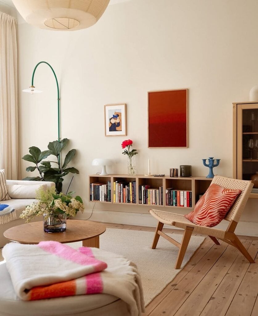 Sala de estar com nicho horizontal com livros, mesa de madeira e luminária de piso