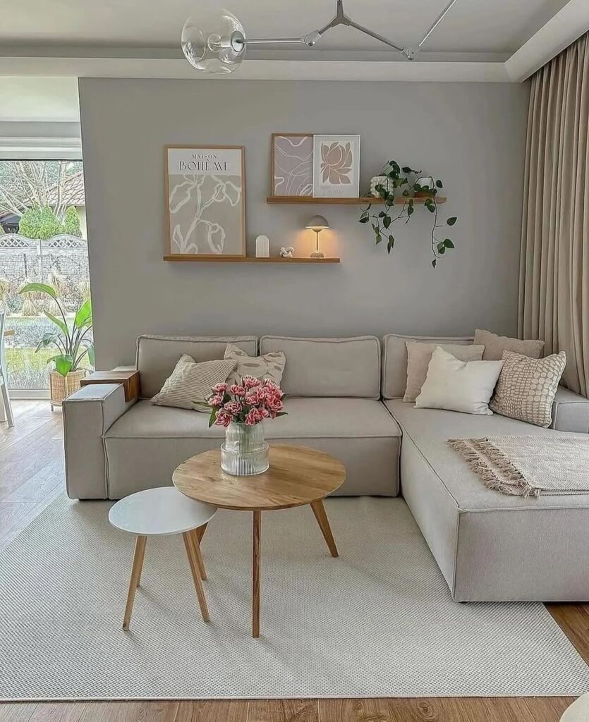 Sala neutra com prateleiras com quadros, planta e abajur, e mesas de centro redondas