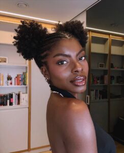 Mulher de pele preta, com blusa preta e cabelo crespo com penteado space buns