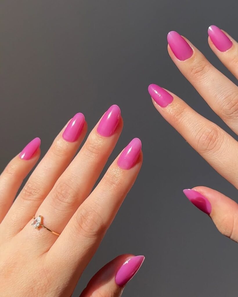 Mãos de pele clara, com anel em dourado e unha amendoada rosa jelly