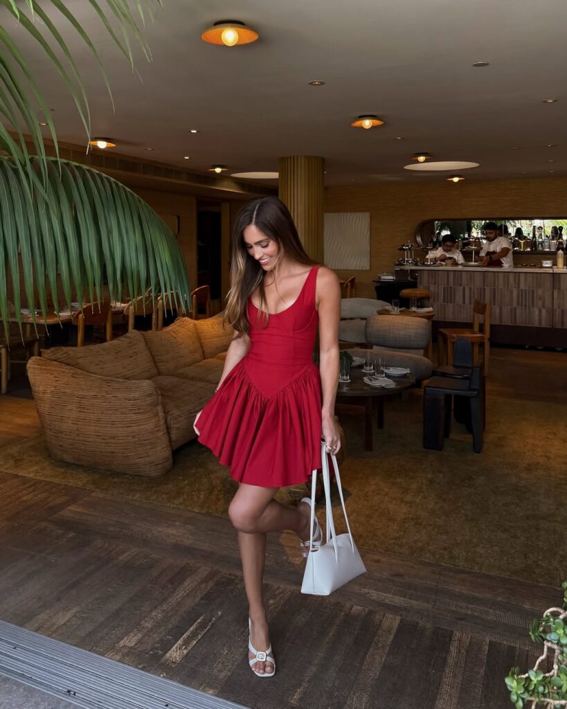 Mulher jovem e magra com vestido vermelho com corset e salto alto branco