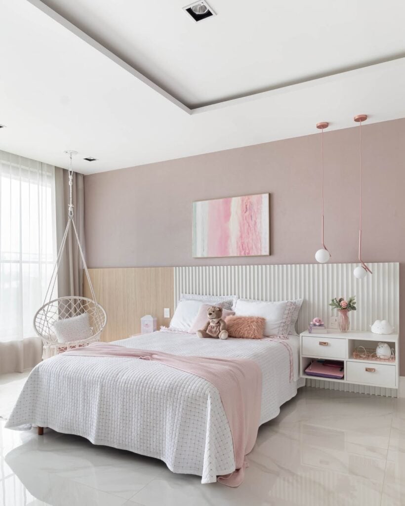 Quarto em branco e tons de rosa com meia parede ripada atrás da cama