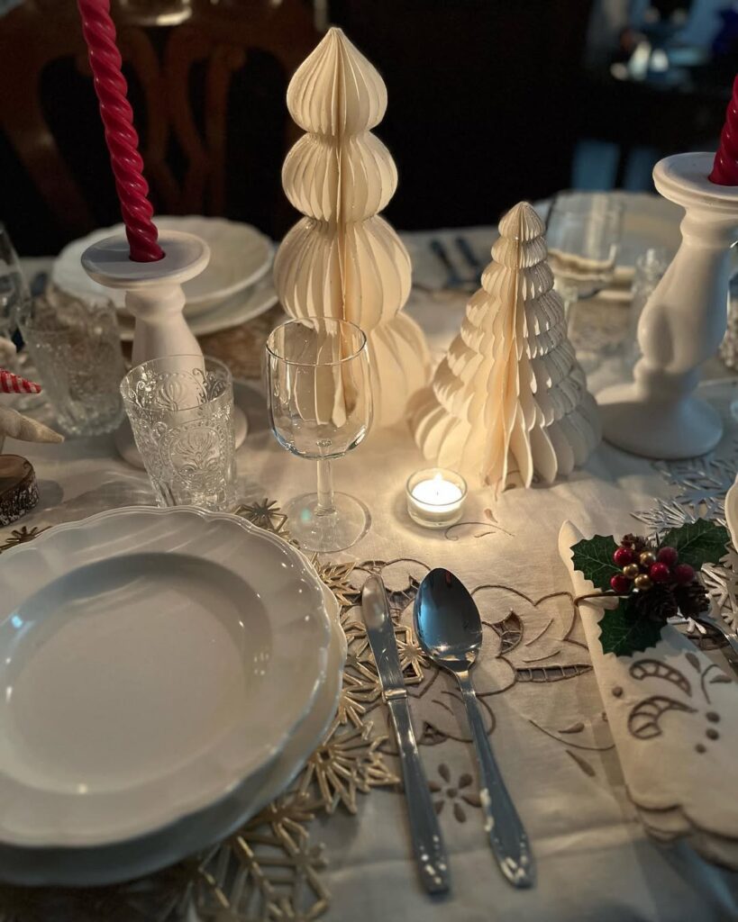 Mesa simples de Natal com toalha e louças brancas, pequenas árvores natalinas de papel