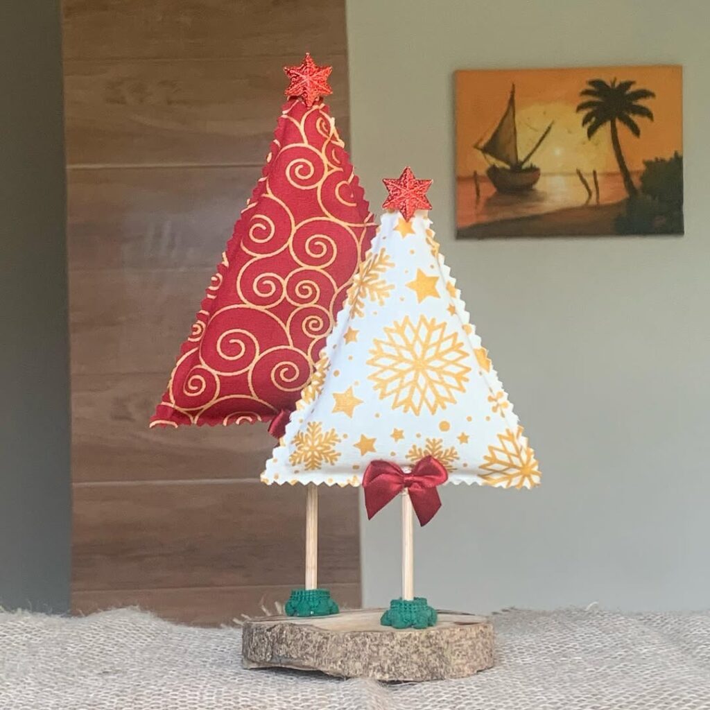 Mini árvore de Natal feita de tecido em cima de um pedacinho de tronco